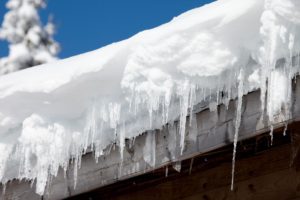 snow and ice hanging off a frozen house roof